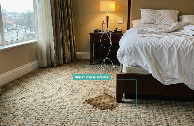 Hotel room with stained carpet and unmade bed.